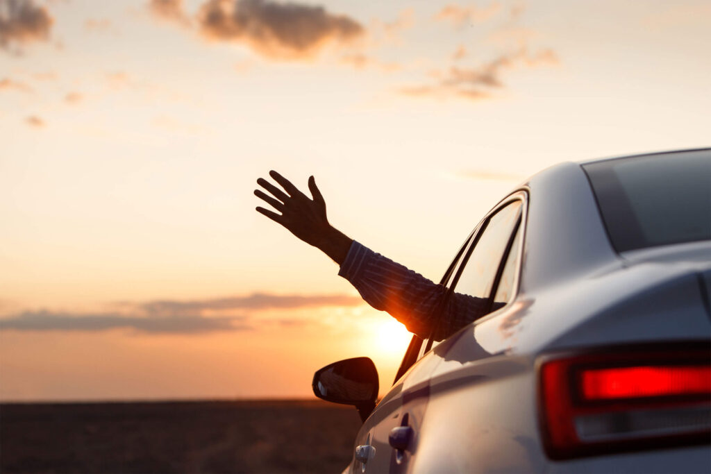 man-inside-car-showing-his-hand-outdoor-leaning-out-car-window-sunset